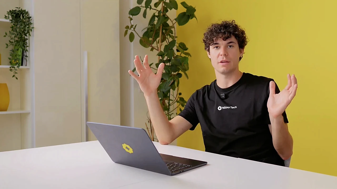 Fermo immagine di una videolezione: una persona del team Yellow Tech parla in camera, seduta al tavolo con il portatile